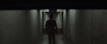 Movie still from “Spiderhead” (2022), directed by Joseph Kosinski – A man in a suit walking down a dark hallway; Wide shot, High angle