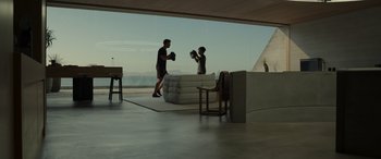 Movie still from “Spiderhead” (2022), directed by Joseph Kosinski – Two people are boxing in a room with a large window; Wide shot, Over the shoulder angle