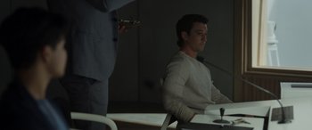 Movie still from “Spiderhead” (2022), directed by Joseph Kosinski – A man sitting at a table in front of a microphone; Medium shot, Over the shoulder angle