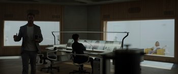 Movie still from “Spiderhead” (2022), directed by Joseph Kosinski – A woman sitting at a desk in front of a monitor; Wide shot, High angle
