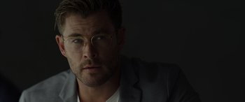 Movie still from “Spiderhead” (2022), directed by Joseph Kosinski – A person wearing a suit and glasses; Close Up shot, Over the shoulder angle