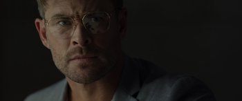 Movie still from “Spiderhead” (2022), directed by Joseph Kosinski – A person wearing glasses and a suit; Close Up shot, Low angle