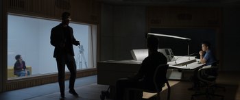 Movie still from “Spiderhead” (2022), directed by Joseph Kosinski – A man sitting in front of a window in a dark room; Wide shot, Over the shoulder angle