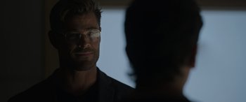 Movie still from “Spiderhead” (2022), directed by Joseph Kosinski – A person wearing glasses looking at the camera; Close Up shot, Over the shoulder angle