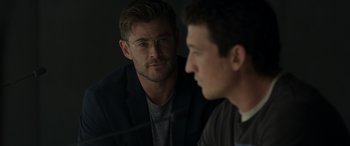 Movie still from “Spiderhead” (2022), directed by Joseph Kosinski – A man and a man wearing glasses looking at one another; Close Up shot, Over the shoulder angle