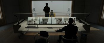 Movie still from “Spiderhead” (2022), directed by Joseph Kosinski – A man sitting in front of a large window; Wide shot, Over the shoulder angle