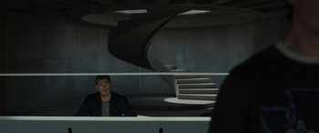 Movie still from “Spiderhead” (2022), directed by Joseph Kosinski – A man sitting in front of a spiral staircase; Wide shot, Low angle