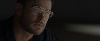 Movie still from “Spiderhead” (2022), directed by Joseph Kosinski – A person wearing glasses; Close Up shot, Low angle