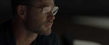 Movie still from “Spiderhead” (2022), directed by Joseph Kosinski – A person wearing a pair of glasses; Close Up shot, Over the shoulder angle