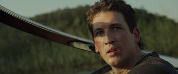 Movie still from “Spiderhead” (2022), directed by Joseph Kosinski – A young man is holding onto a canoe paddle; Close Up shot, Low angle