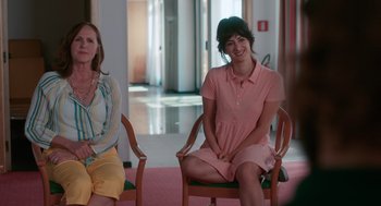 Movie still from “Spin Me Round” (2022), directed by Jeff Baena – Two women sitting in chairs in a room; Medium shot, Over the shoulder angle