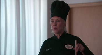 Movie still from “Spin Me Round” (2022), directed by Jeff Baena – A woman wearing a chef's hat while holding a spoon; Close Up shot, Over the shoulder angle
