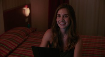 Movie still from “Spin Me Round” (2022), directed by Jeff Baena – A woman sitting on a bed with a laptop in front of her face; Close Up shot, Over the shoulder angle
