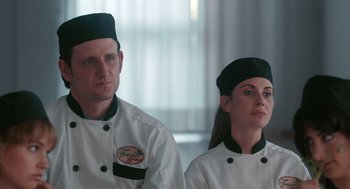 Movie still from “Spin Me Round” (2022), directed by Jeff Baena – A man and a woman in chef's outfits; Close Up shot, Low angle