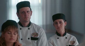 Movie still from “Spin Me Round” (2022), directed by Jeff Baena – A man and a woman in chef's outfits; Close Up shot, Over the shoulder angle