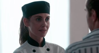 Movie still from “Spin Me Round” (2022), directed by Jeff Baena – A woman in a chef's outfit looking at a camera; Close Up shot, Over the shoulder angle