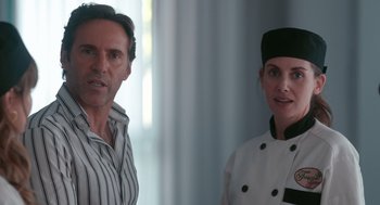 Movie still from “Spin Me Round” (2022), directed by Jeff Baena – A man and a woman standing next to each other; Close Up shot, Over the shoulder angle