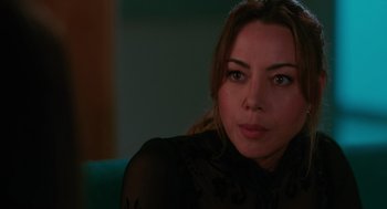 Movie still from “Spin Me Round” (2022), directed by Jeff Baena – A person wearing a black shirt; Close Up shot, Over the shoulder angle