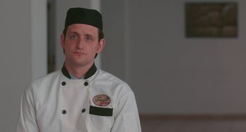 Movie still from “Spin Me Round” (2022), directed by Jeff Baena – A man in a chef's outfit is looking at the camera; Close Up shot, Low angle
