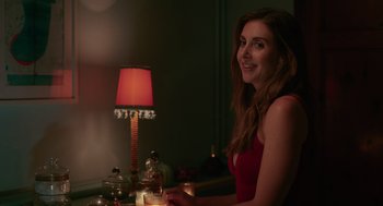 Movie still from “Spin Me Round” (2022), directed by Jeff Baena – A woman sitting in front of a table with candles; Close Up shot, Over the shoulder angle