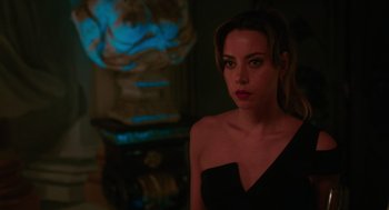 Movie still from “Spin Me Round” (2022), directed by Jeff Baena – A woman in a black dress is standing in a room; Close Up shot, Over the shoulder angle