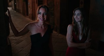 Movie still from “Spin Me Round” (2022), directed by Jeff Baena – Two beautiful women standing next to each other on a sidewalk; Medium shot, Over the shoulder angle