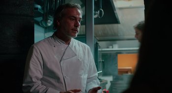 Movie still from “Spin Me Round” (2022), directed by Jeff Baena – A man in a chef's outfit talking to a woman; Close Up shot, Low angle