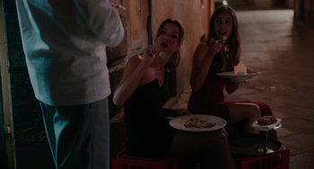 Movie still from “Spin Me Round” (2022), directed by Jeff Baena – Two women sitting in front of a plate of food; Medium shot, Over the shoulder angle