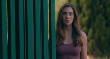 Movie still from “Spin Me Round” (2022), directed by Jeff Baena – A beautiful woman standing next to a green fence; Close Up shot, Over the shoulder angle