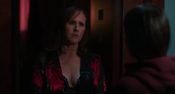 Movie still from “Spin Me Round” (2022), directed by Jeff Baena – A woman in a black and red dress looking at a mirror; Close Up shot, Over the shoulder angle