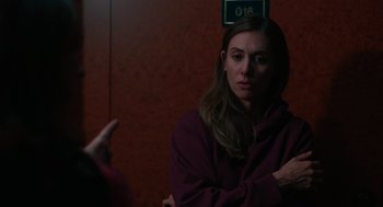 Movie still from “Spin Me Round” (2022), directed by Jeff Baena – A woman in a purple jacket is talking to someone; Close Up shot, Over the shoulder angle