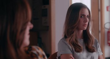 Movie still from “Spin Me Round” (2022), directed by Jeff Baena – A woman sitting in front of another woman in front of a window; Close Up shot, Over the shoulder angle