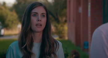 Movie still from “Spin Me Round” (2022), directed by Jeff Baena – A beautiful young lady with long brown hair and blue eyes; Close Up shot, Over the shoulder angle