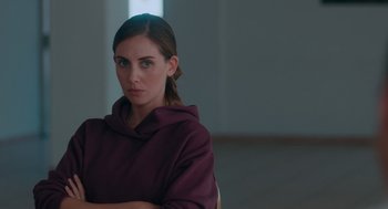 Movie still from “Spin Me Round” (2022), directed by Jeff Baena – A woman in a purple hoodie posing for a picture; Close Up shot, Over the shoulder angle