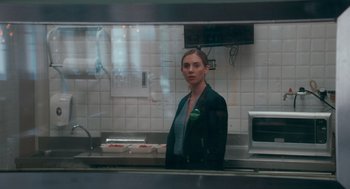 Movie still from “Spin Me Round” (2022), directed by Jeff Baena – A woman standing in front of a counter in a kitchen; Close Up shot, Over the shoulder angle