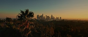 Movie still from “Spinning Gold” (2023), directed by Timothy Scott Bogart – A view of a city skyline at sunset from a hill; Extreme Wide shot, High angle