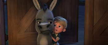Movie still from “Spirit Untamed” (2021), directed by Ennio Torresan – A boy and a donkey are standing next to each other; Close Up shot, Over the shoulder angle