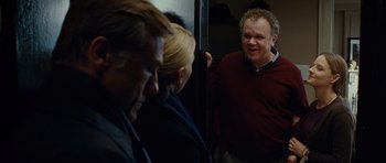 Movie still from “Carnage” (2011), directed by Roman Polanski – A man standing next to two other people; Medium shot, Over the shoulder angle