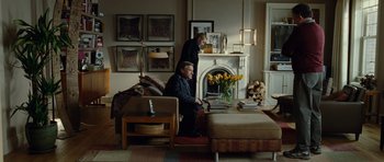 Movie still from “Carnage” (2011), directed by Roman Polanski – Two men are sitting in a living room with a fire place; Wide shot, Over the shoulder angle