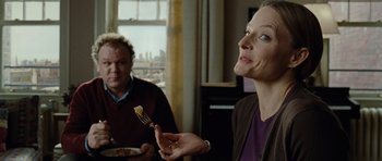 Movie still from “Carnage” (2011), directed by Roman Polanski – A woman holding a fork in her right hand while sitting next to a man; Close Up shot, Over the shoulder angle