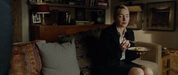 Movie still from “Carnage” (2011), directed by Roman Polanski – A woman sitting on a couch holding a cell phone; Medium shot, High angle
