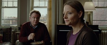 Movie still from “Carnage” (2011), directed by Roman Polanski – A man and a woman sitting at a table with a plate of food in front of them; Close Up shot, Over the shoulder angle