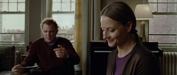 Movie still from “Carnage” (2011), directed by Roman Polanski – Two people in a room with a window in the background; Medium shot, Over the shoulder angle