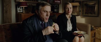 Movie still from “Carnage” (2011), directed by Roman Polanski – A man and a woman sitting next to each other; Medium shot, Over the shoulder angle