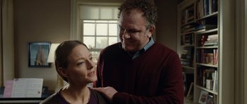 Movie still from “Carnage” (2011), directed by Roman Polanski – A man and a woman standing next to each other in front of a window; Medium shot, Low angle