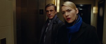 Movie still from “Carnage” (2011), directed by Roman Polanski – A man and a woman standing next to each other in front of an elevator; Close Up shot, Low angle