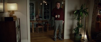 Movie still from “Carnage” (2011), directed by Roman Polanski – A man holding a coffee cup in a room; Wide shot, Low angle
