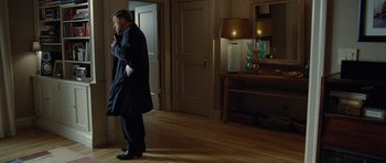 Movie still from “Carnage” (2011), directed by Roman Polanski – A man standing in front of a door in a room; Medium shot, Over the shoulder angle