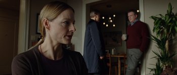 Movie still from “Carnage” (2011), directed by Roman Polanski – A woman standing in front of a man in a dark room; Medium shot, Over the shoulder angle