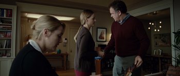 Movie still from “Carnage” (2011), directed by Roman Polanski – A man and a woman standing next to each other in a living room; Medium shot, Over the shoulder angle